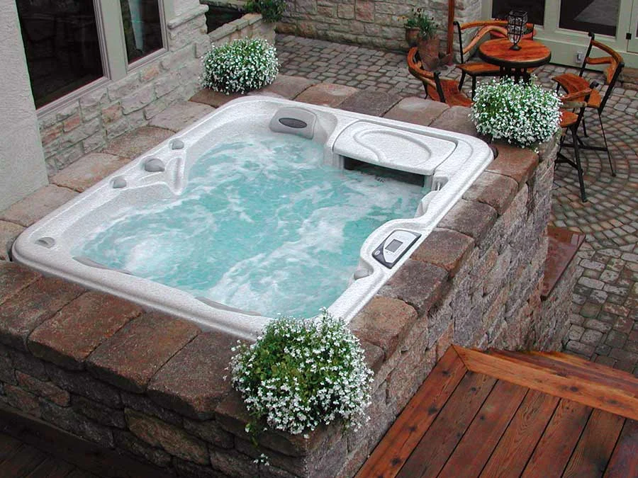 Outdoor hot tub with bubbling water in a stone patio setting from High Elevation Hot Tubs