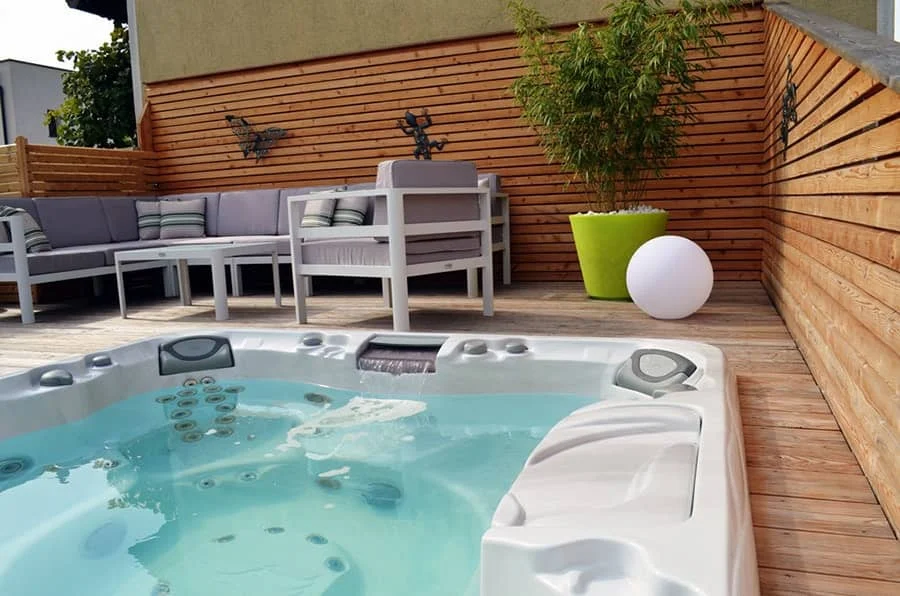 Outdoor hot tub on a wood deck with patio seating from High Elevation Hot Tubs