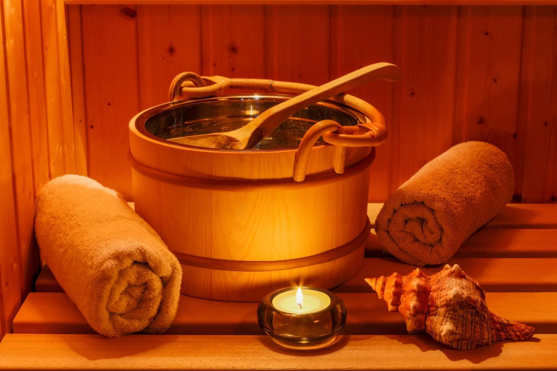 Wooden sauna bucket, towels, candle, and seashells from High Elevation Hot Tubs